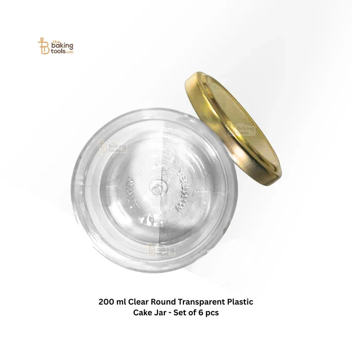 Clear round transparent plastic cake jar with gold lid on a white background