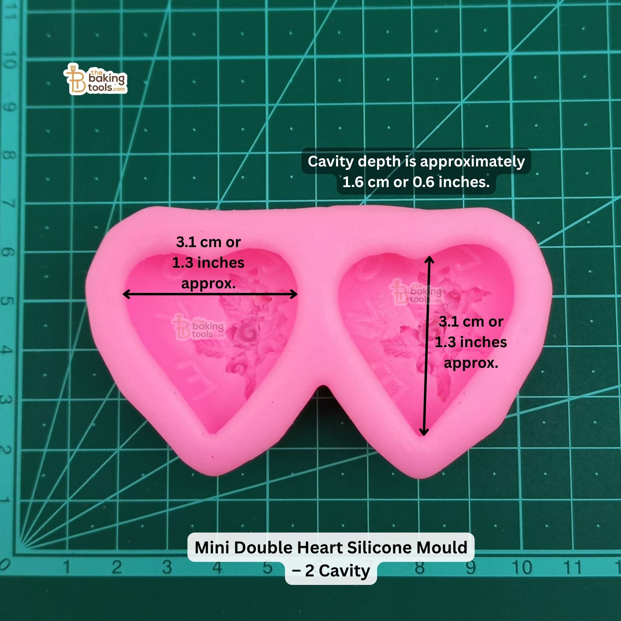Pink mini double heart silicone mold on a green cutting mat with measurements.