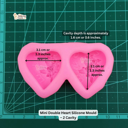 Pink mini double heart silicone mold on a green cutting mat with measurements.