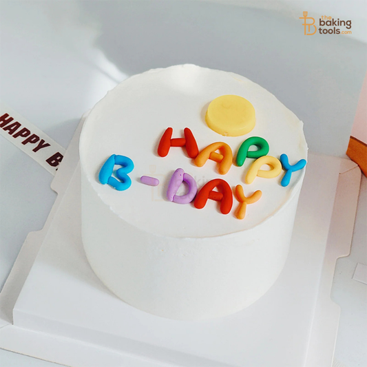 White cake with colorful 'HAPPY B-DAY' letters on a white background