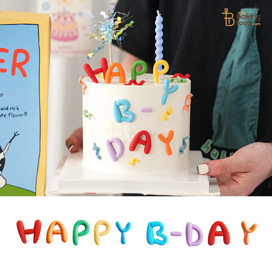 Birthday cake with colorful letters spelling 'HAPPY B-DAY' held by a person.